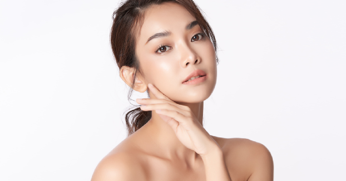 Young woman with flawless skin gently touching her face, showcasing a smooth, glowing complexion after a Préime Derma Facial in Leesburg, FL.